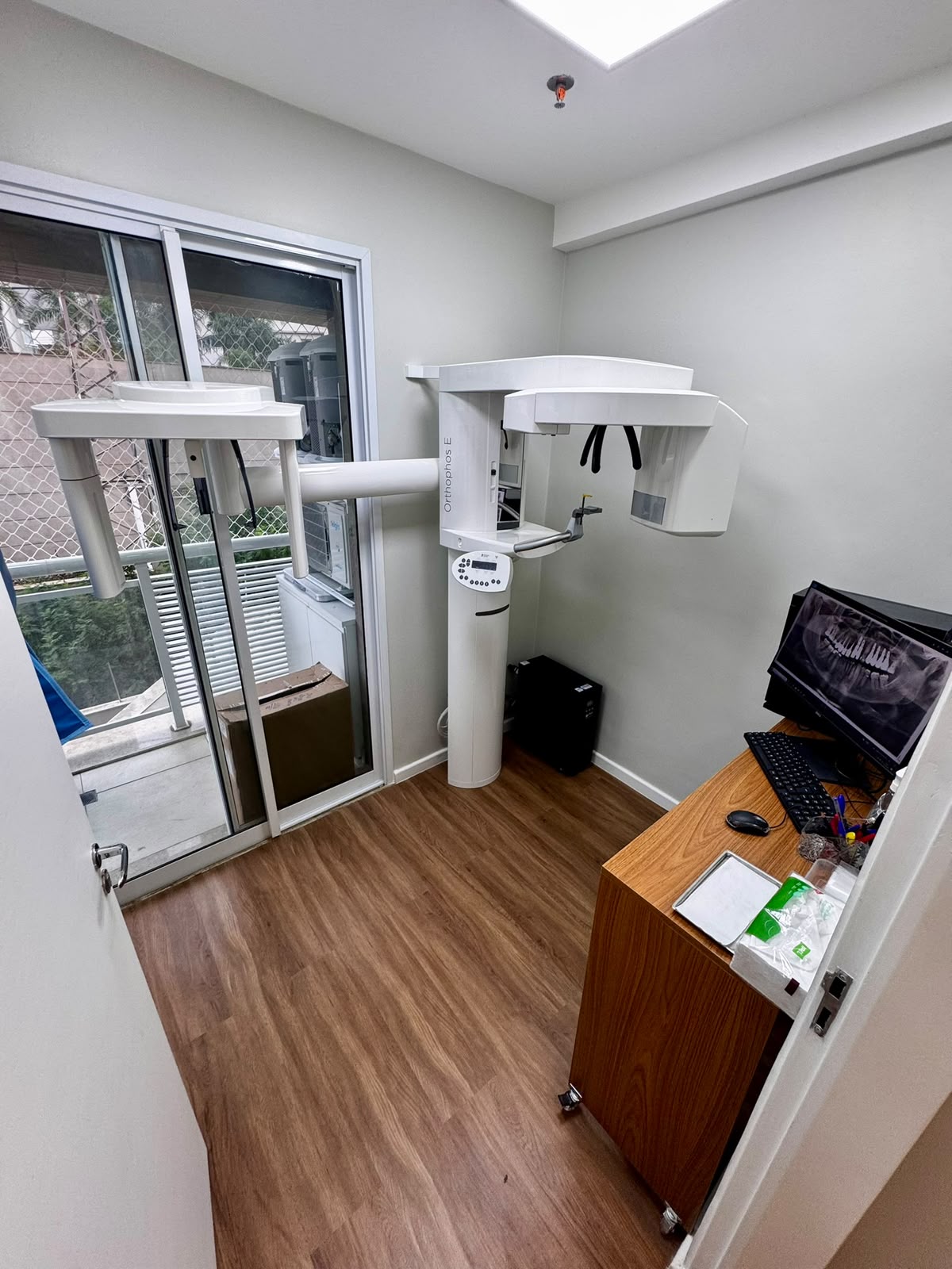 Sala de radiografia panorâmica digital com equipamento Orthophos e imagem no monitor
