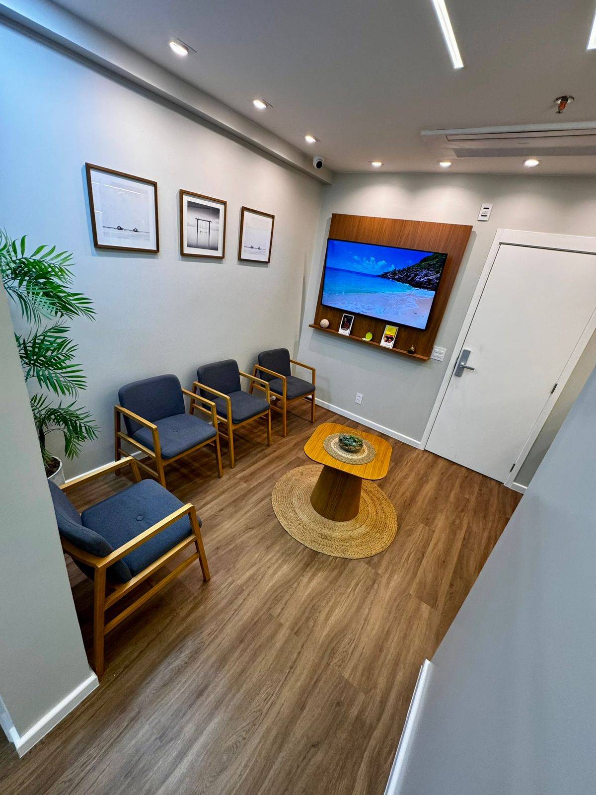 Recepção da clínica Dra. Joyce Martins com poltronas, quadros e televisão