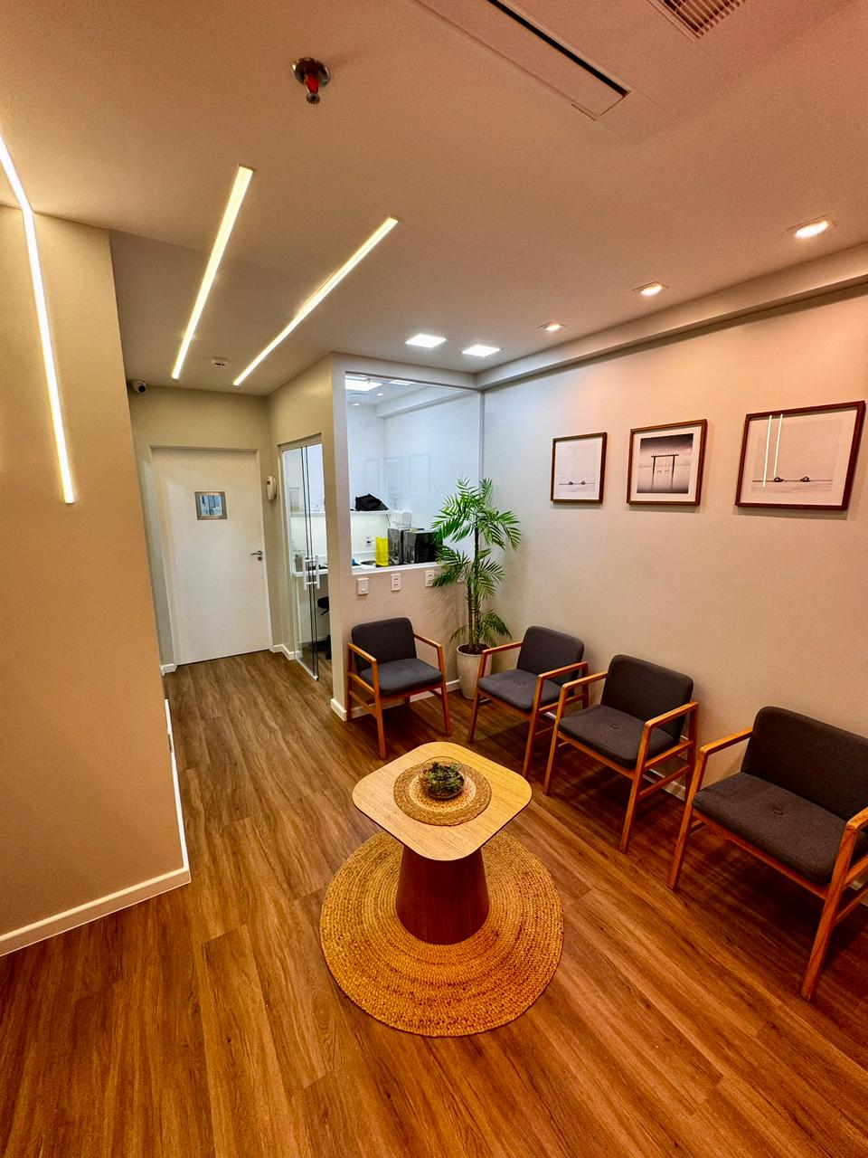 Sala de espera da clínica com iluminação suave, plantas e mesa de centro